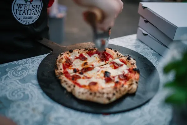 Freshly sliced pepperoni pizza from our wood-fired oven